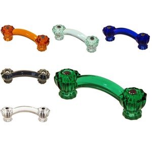 May include: A collection of colorful cabinet pulls in various hues, including orange, white, blue, black, clear, and green. Each pull features a curved handle and decorative, faceted end pieces, offering a vintage aesthetic.
