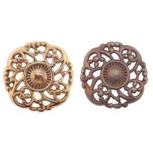 May include: Two decorative metal knobs with a filigree design. One knob is gold and the other is brown.