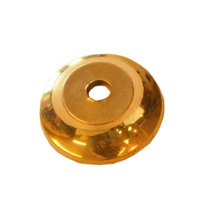 May include: A gold-colored metal cap with a round hole in the center. The cap is smooth and shiny.