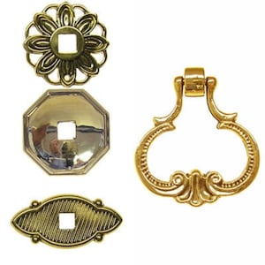 May include: Four gold-toned metal drawer pulls with ornate designs. The pulls have a square hole in the center for a screw.