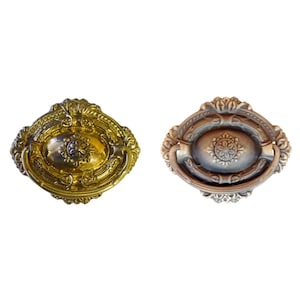 May include: Two ornate oval-shaped cabinet door pulls. One is gold with a silver center and the other is a dark bronze with a silver center.