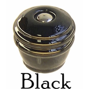 May include: Black ceramic cabinet knob with a silver metal center. The knob has a rounded top and a slightly raised edge.
