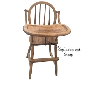 May include: Wooden high chair with a tray and a replacement strap. The chair is made of natural wood and has a simple design.