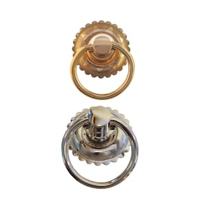 May include: Two decorative ring pulls, one gold and one silver, with a detailed, scalloped edge and a ring handle.