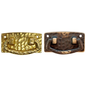 May include: Two cabinet pulls with a hammered finish. The pull on the left is gold and the pull on the right is brown.