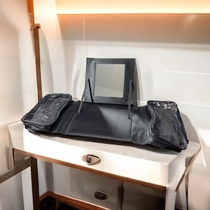 以下が含まれることがあります： 鏡が内蔵された黒い旅行用メイクケース。ケースは3つのコンパートメントに分かれており、鏡が見えるように開いています。