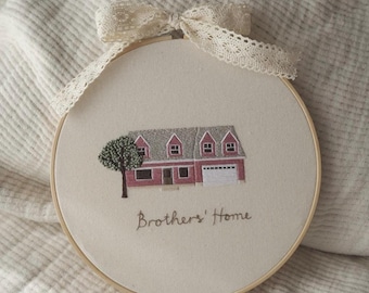 May include: Embroidered hoop art featuring a red house with a green tree and the text "Brothers' Home".