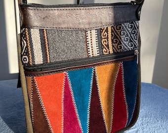 May include: A brown leather crossbody bag with a colorful patchwork design. The bag has a zipper closure and a strap with the word "Bolivia" embossed on it.