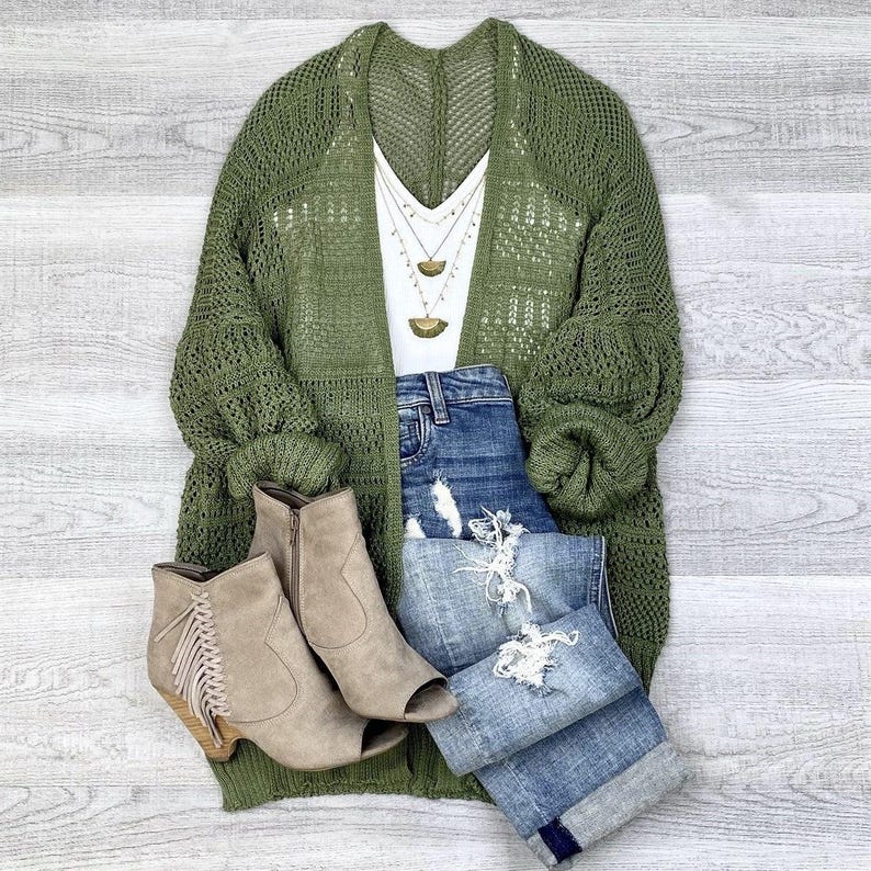 May include: A green open knit cardigan with long sleeves and a white tank top underneath. The cardigan is paired with blue denim jeans and brown suede peep-toe booties.