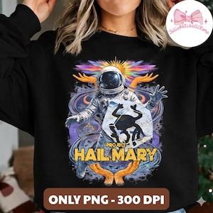 Puede incluir: Sudadera negra con un gráfico colorido de un astronauta, un sol y el texto "PROJECT HAIL MARY". El diseño incluye una rana estilizada y el texto "ONLY PNG - 300 DPI".