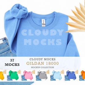 Puede incluir: Una sudadera Gildan 18000 azul claro con el texto "Cloudy Mocks" en una fuente azul claro. La sudadera se combina con unos vaqueros azules y una scrunchie azul claro. La imagen también incluye una colección de maquetas de 37 maquetas.