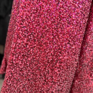 Puede incluir: Primer plano de una tela rosa con lentejuelas. Las lentejuelas son peque&ntilde;as y est&aacute;n densamente empaquetadas, creando un efecto brillante.
