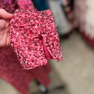 Puede incluir: Primer plano de una tela rosa con lentejuelas con una peque&ntilde;a abertura en la tela. Las lentejuelas son peque&ntilde;as y est&aacute;n muy juntas.