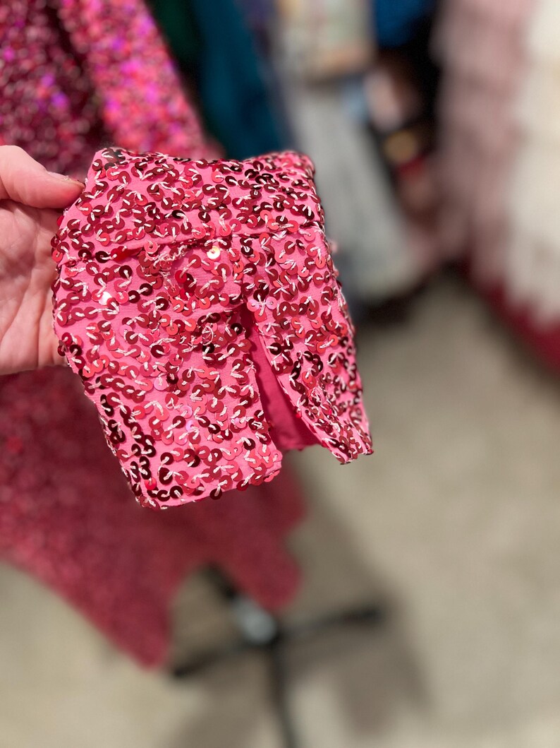 Puede incluir: Primer plano de una tela rosa con lentejuelas con una peque&ntilde;a abertura en la tela. Las lentejuelas son peque&ntilde;as y est&aacute;n muy juntas.