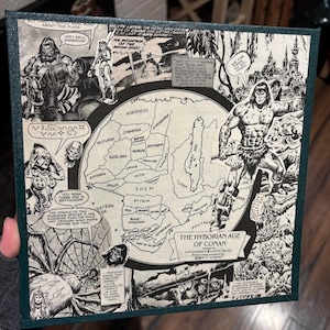 May include: A black and white map of the Hyborian Age of Conan, a fictional world from the Conan the Barbarian series. The map shows various kingdoms and regions, including Shem, Stygia, Aquilonia, and Cimmeria. The map is surrounded by comic book panels featuring Conan and other characters.