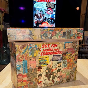 May include: A vintage comic book themed storage box with a colorful collage of comic book panels featuring Sgt. Fury and his Howling Commandos. The box is made of cardboard and has a hinged lid.