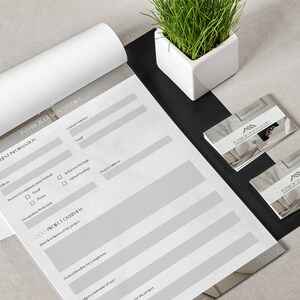 May include: A white sheet of paper with a gray background, titled "Client Information" and "Project Overview." The paper has blank lines for filling in information. Two business cards are on a black surface, with the text "Room & Co. Interiors" on each card.