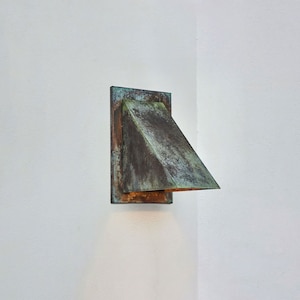 May include: A copper-toned wall sconce with a triangular shade, mounted on a white wall.