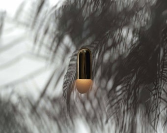May include: A gold pendant light fixture with a white frosted glass shade hangs from a ceiling, casting a shadow of palm leaves on a white wall.
