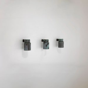 May include: Three wall-mounted lights with a weathered copper finish. The lights are cylindrical in shape and have a slightly angled design.