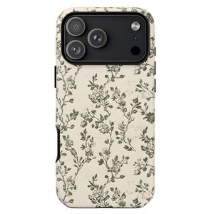 Puede incluir: Funda de tel&eacute;fono con dise&ntilde;o floral. La funda tiene un fondo color crema con un patr&oacute;n de flores y enredaderas verdes y blancas. El &aacute;rea de la c&aacute;mara es negra.