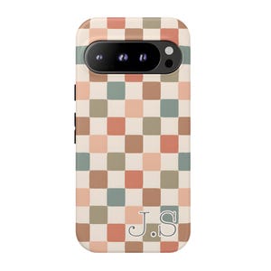 May include: A phone case with a checkerboard pattern in shades of brown, peach, green, and cream. The case has a camera cutout and the initials "J.S" at the bottom. The case is designed to fit a smartphone.