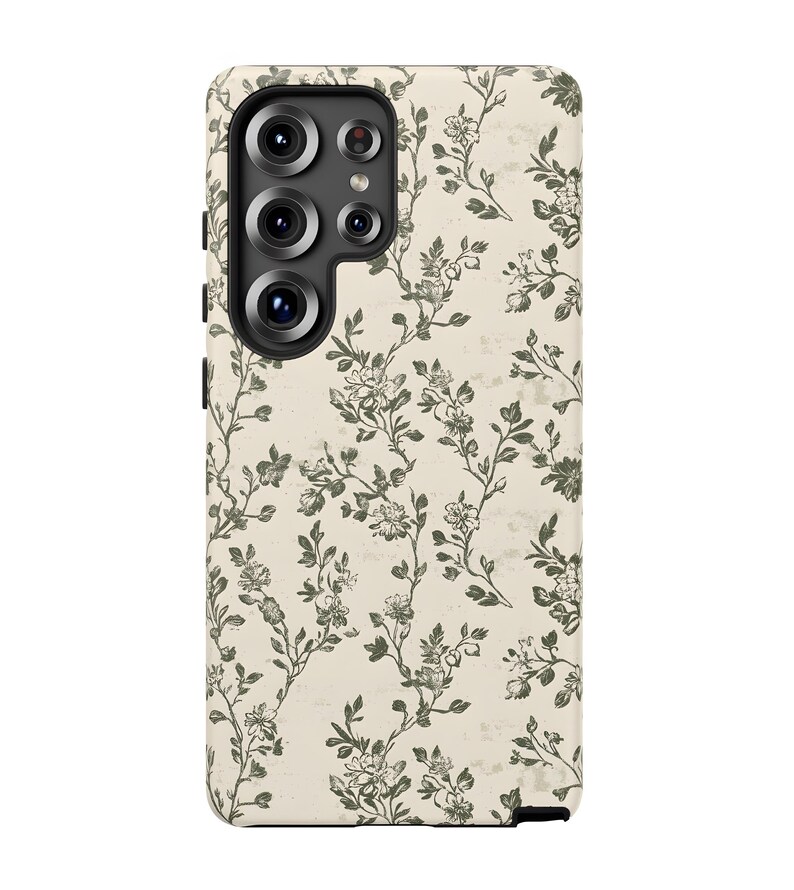 Puede incluir: Una funda de tel&eacute;fono con un estampado floral. La funda es de color beige claro con un dise&ntilde;o repetido de ramas florales verdes. Las lentes de la c&aacute;mara son visibles en la parte superior izquierda.