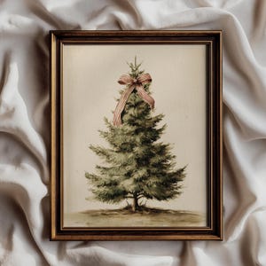 May include: A framed wall art print featuring a watercolor-style illustration of a green pine tree centered on a cream background. The tree is adorned with a single red and white striped ribbon bow at the top, encased in a dark brown wooden frame.
