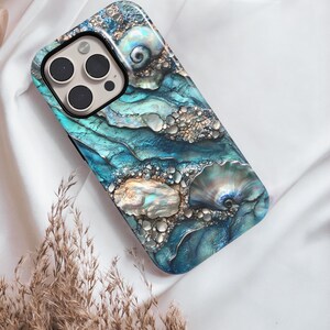 May include: A blue and gold iPhone case with a seashell design. The case has a textured surface and a camera cutout.