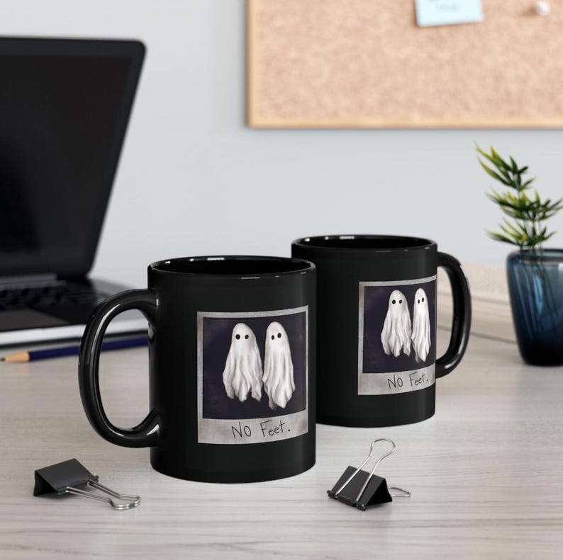 May include: Two black coffee mugs with a white ghost design and the text "No Feet." printed on them.