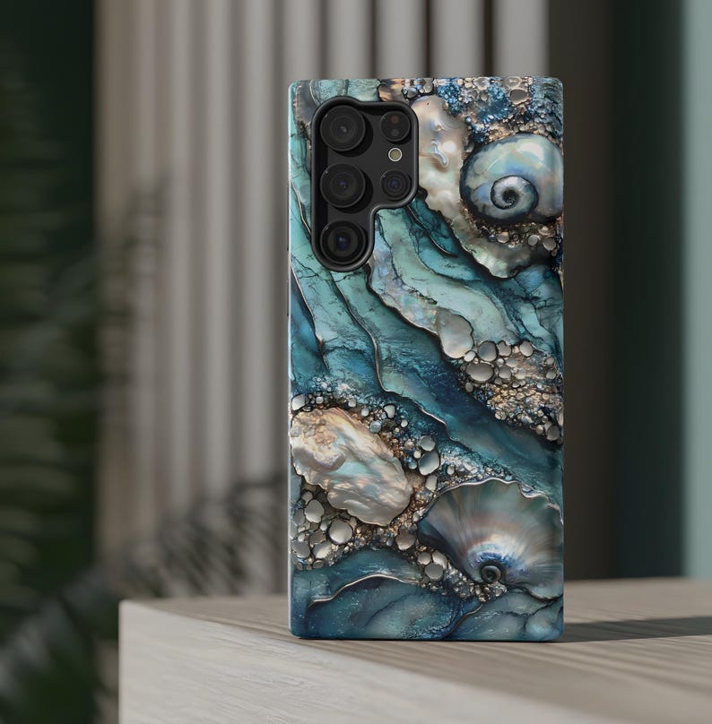 May include: A blue and white phone case with a seashell design. The case has a camera cutout and a textured surface.