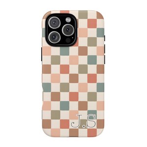 May include: A phone case with a checkerboard pattern in shades of beige, peach, green, and brown. The case has a camera cutout and the initials "J.S" in a serif font at the bottom.