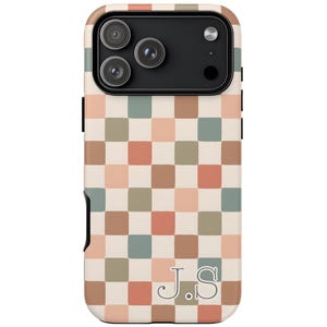 May include: A phone case with a checkerboard pattern in shades of beige, peach, green, and brown. The case has a black camera module and the initials "J.S." are printed in a serif font at the bottom.