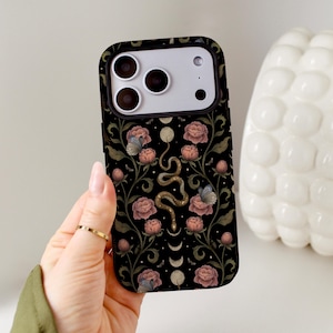 May include: A black smartphone case featuring a central golden snake winding vertically among pink peony flowers, green leafy vines, and small butterflies. The design includes a vertical series of moon phases in white and cream tones against the dark background.