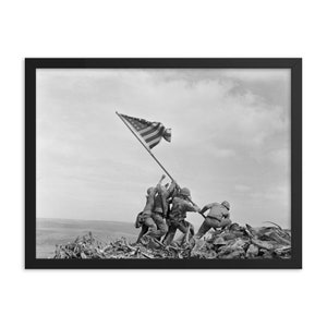 May include: Black and white photograph of four soldiers raising the American flag on a hilltop. The flag is waving in the wind. The soldiers are wearing military uniforms and look determined.