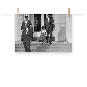Może przedstawiać: Czarno-białe zdjęcie młodej dziewczyny w sukience idącej po schodach budynku, eskortowanej przez dwóch mężczyzn w garniturach. Dziewczynka niesie plecak i uśmiecha się. Mężczyźni patrzą prosto przed siebie.