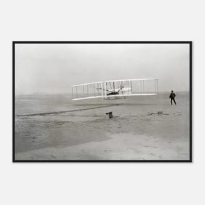 May include: A black and white photograph of the Wright brothers' first flight. The biplane is airborne, with a person running alongside it. The scene is set on a sandy surface under a cloudy sky.