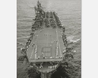 Pode incluir: Fotografia a preto e branco de um grande porta-aviões no mar. O convés do porta-aviões está cheio de aviões e pessoal. O número "9" está pintado no convés. O navio está rodeado por água.