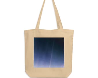 Op de afbeelding: Een beige tote bag met een blauwe en zwarte afbeelding van de aarde vanuit de ruimte. De afbeelding toont een dunne blauwe lijn die de atmosfeer voorstelt.