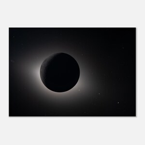 May include: A black celestial body, possibly a planet or moon, is centered in a dark space. A bright, white halo surrounds the object, creating a striking contrast. Small, distant stars are visible in the background.
