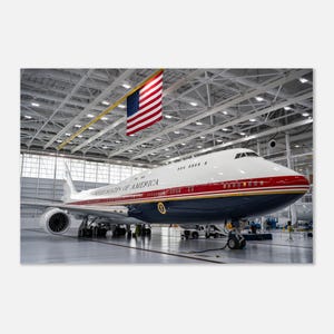 Może przedstawiać: Duży biało-czerwono-niebieski samolot z napisem UNITED STATES OF AMERICA na boku, zaparkowany w hangarze. Pod sufitem nad samolotem wisi duża amerykańska flaga, a na kadłubie widnieje pieczęć prezydencka.