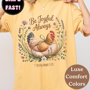 A woman wearing a yellow t-shirt with a graphic design of a chicken surrounded by flowers and greenery.