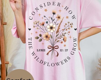 May include: Pink oversized t-shirt with a floral design and the text "Consider how the wildflowers grow" with a verse from Luke 12:27.