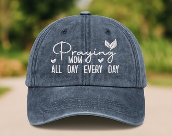 以下が含まれることがあります： 白い刺繍で「Praying Mom All Day Every Day」と書いてある、青いデニムの野球帽。小さな葉とハートのデザインが施されています。