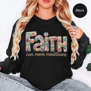 May include: Black sweatshirt featuring the word "Faith" in a floral design, with the text "can move mountains" underneath. The sweatshirt also has the text "Matthew 21:22".