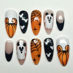 May include: Set of ten Halloween-themed press-on nails with various designs, including pumpkins, ghosts, Mickey Mouse ears, and spiderwebs. The nails are in a variety of colors, including orange, black, white, and nude.