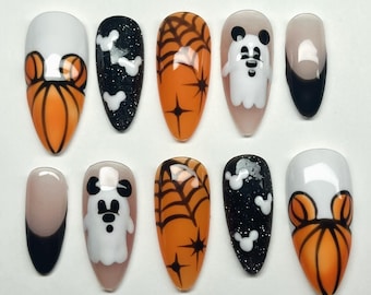 May include: Set of ten Halloween-themed press-on nails with various designs, including pumpkins, ghosts, Mickey Mouse ears, and spiderwebs. The nails are in a variety of colors, including orange, black, white, and nude.