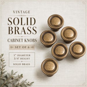 May include: A set of six round cabinet knobs made of solid brass with an aged finish. The text on the image reads: VINTAGE SOLID BRASS CABINET KNOBS SET OF 6, 1 inch diameter, 3/4 inch height, SOLID BRASS. The knobs have a smooth, circular design.