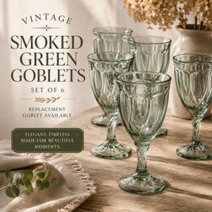 May include: A set of six smoked green goblets with a vintage design. The elegant glassware is displayed on a wooden surface, with text that reads "Vintage Smoked Green Goblets". The goblets are made for beautiful moments.