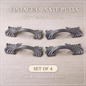 May include: Set of four vintage ornate pulls in a French Provincial style. Each pull is a dark metallic color with decorative scrollwork and measures 4.25 inches center to center. The pulls are arranged on a light gray background.